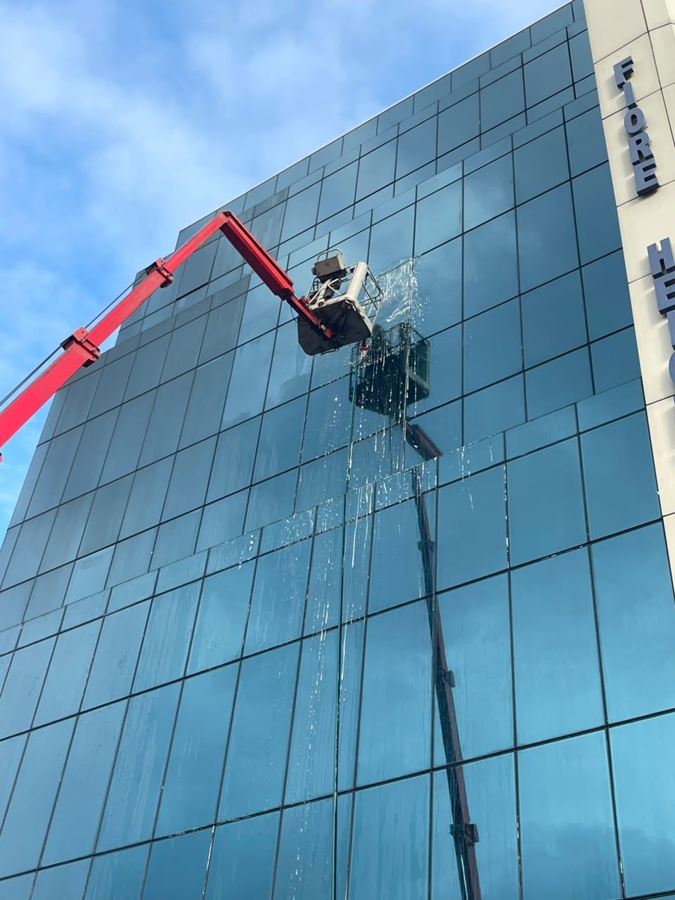 Boom lift washing the glass tower at Fiore Heights, Accra