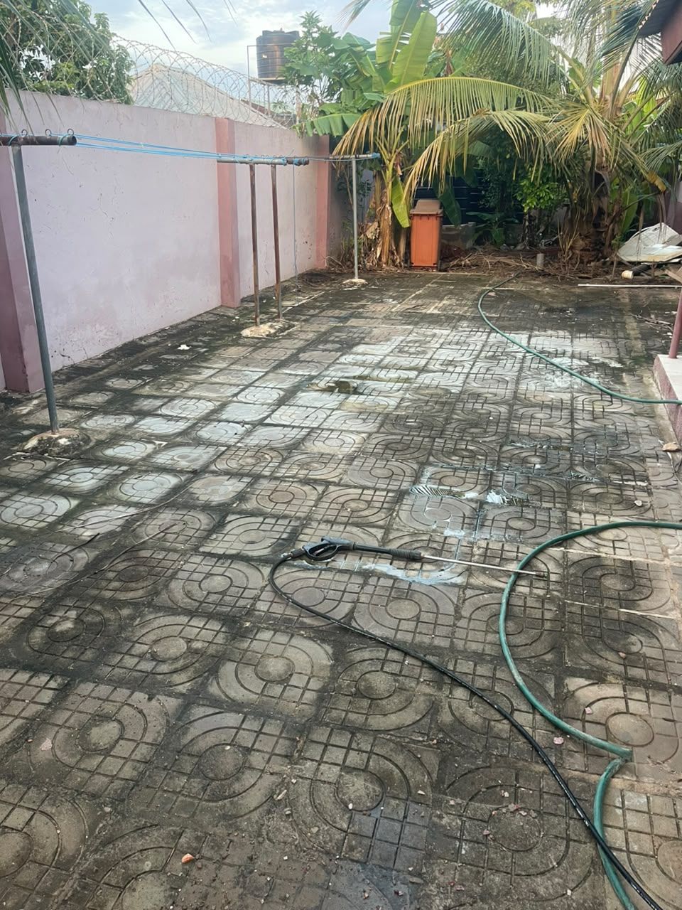 A compound dark with dirt and algae before HFJS pressure washing, Accra